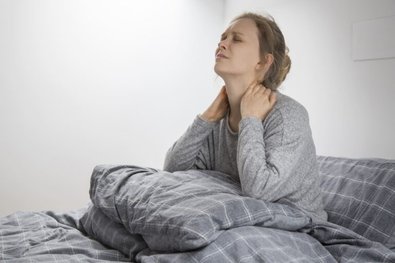 tired woman waking up with neck pain touching her neck suffering from pain