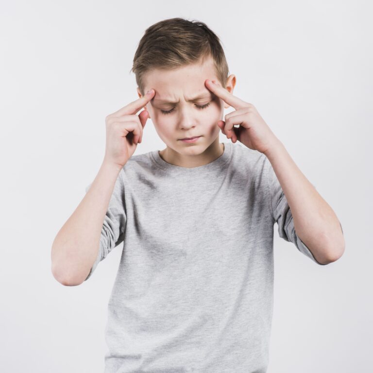 Young boy pressing his temples with both hands showing signs of migraines in children